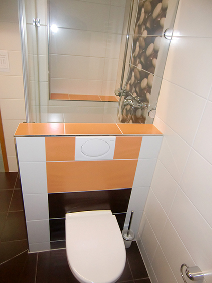 Modernes Badezimmer weiß gefliest, aufgelockert mit farbigen, orangen